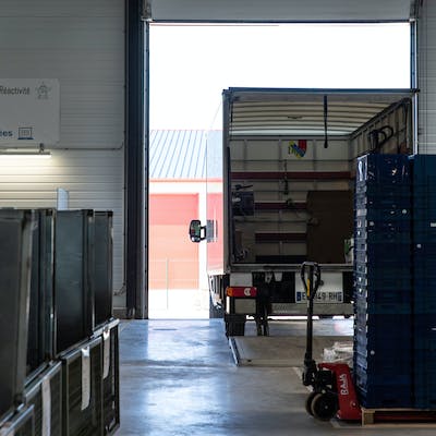 Un camion déchargeant des colis dans un entrepôt logistique omnicanal